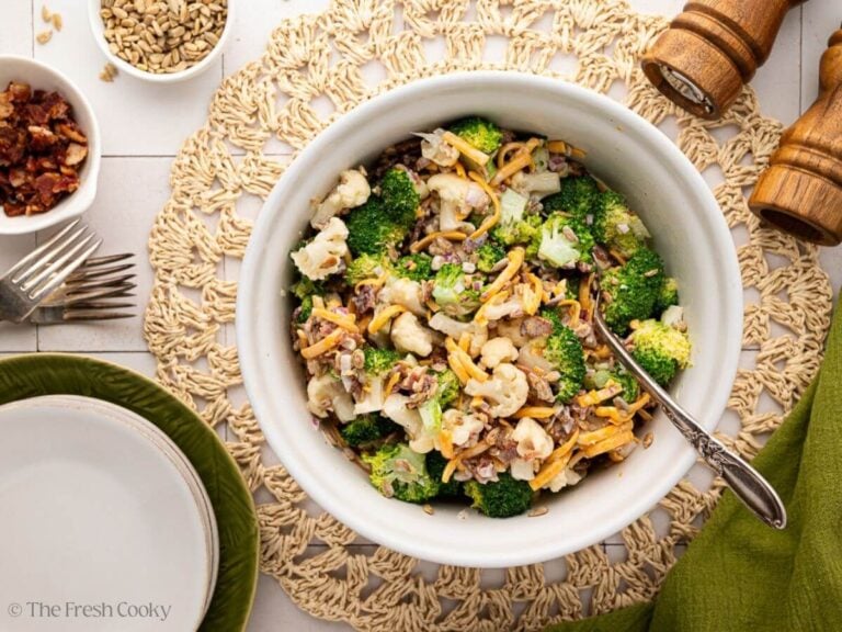 Broccoli cauliflower salad served in a large bowl with a serving spoon.