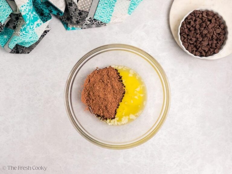 A glass bowl with melted butter and cocoa powder with a bowl of chocolate chips.