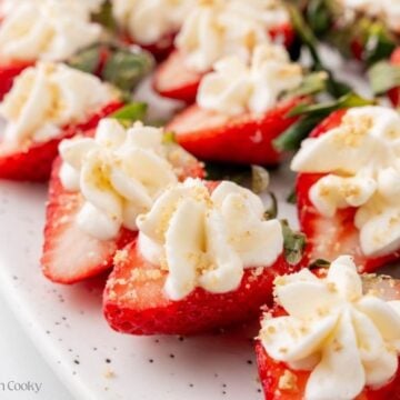 Deviled strawberries lined up on a serving platter, garnished with graham crackers.