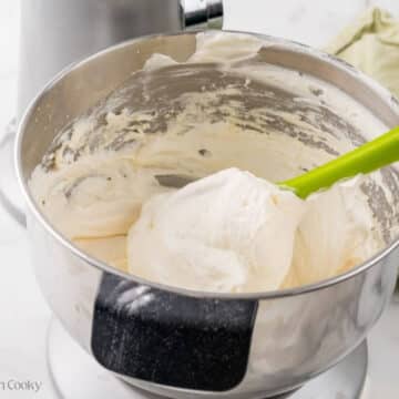 Folding in the whipped cream into the cream cheese mixture.