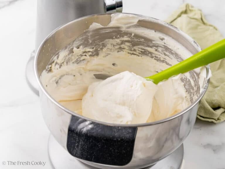 Folding in the whipped cream into the cream cheese mixture.
