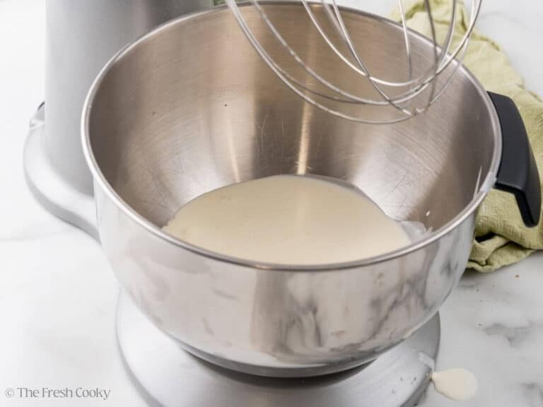 Heavy cream in the bowl of a stand mixer.
