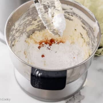 Powdered sugar and vanilla added to the cream cheese in the bowl of a stand mixer.