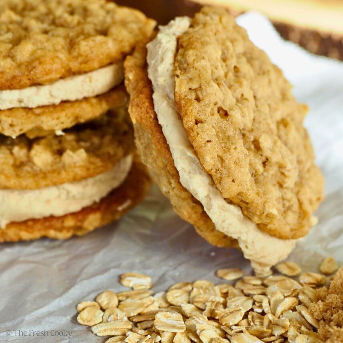 Two stacked oatmeal sandwich cookies with a third leaning up against them.