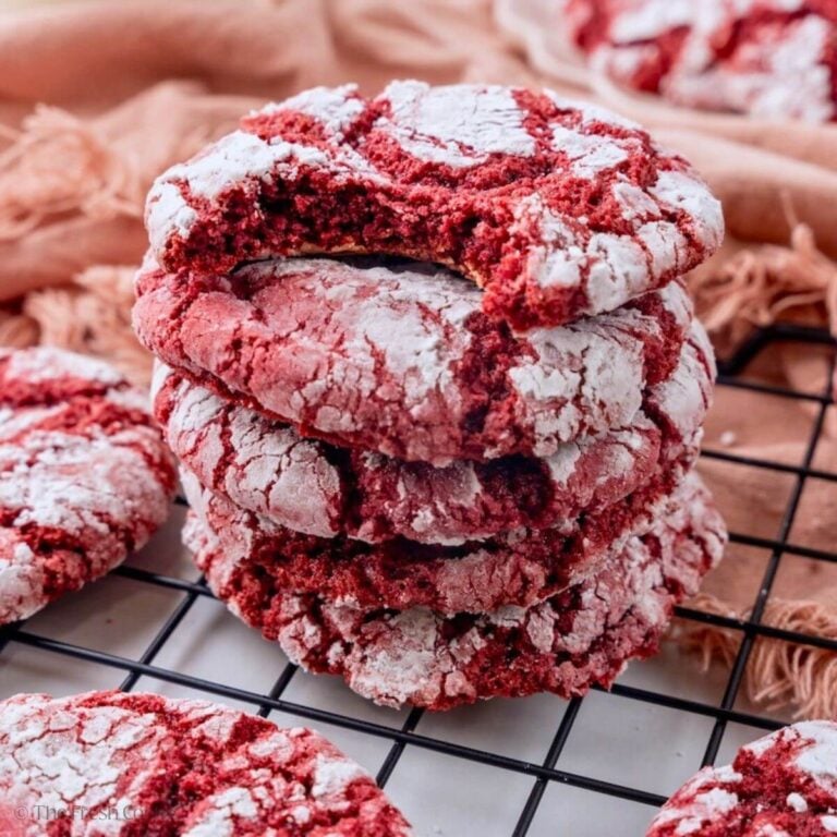 Stack of red velvet crinkle cookies with the one on the top missing a bite.