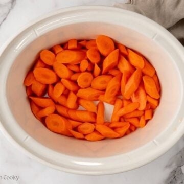 Sliced carrots placed in the bottom of a slow cooker.