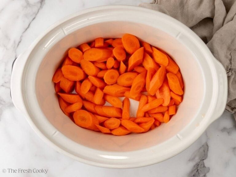 Sliced carrots placed in the bottom of a slow cooker.