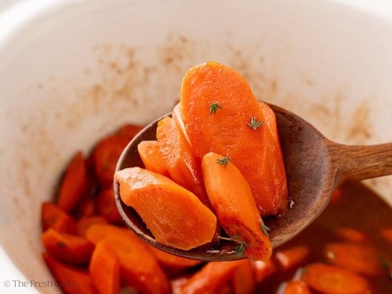 Wooden spoon with slow cooker glazed carrots on it.