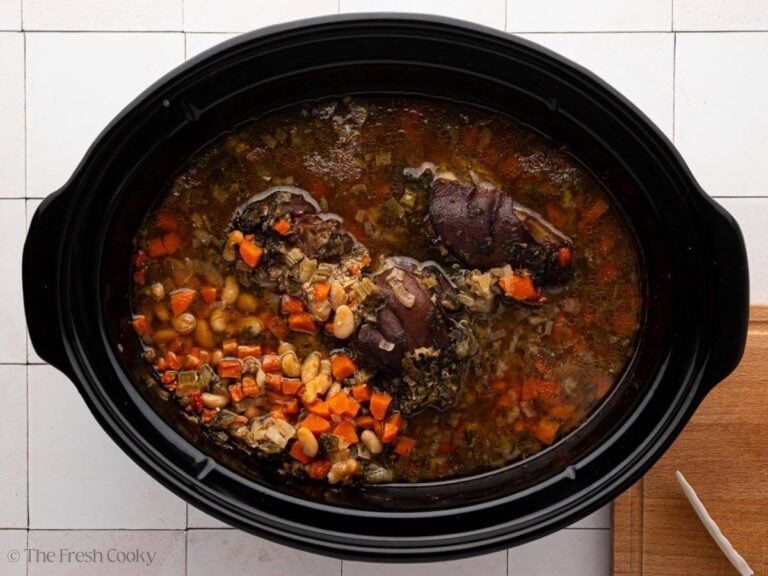 A black crock pot bowl with slow cooker ham and bean soup.