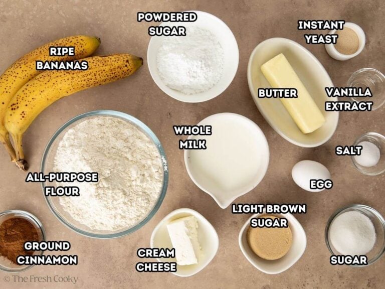Labeled ingredients for banana bread cinnamon rolls, L-R ripe bananas, powdered sugar, butter, yeast, egg, milk, cinnamon, all purpose flour.