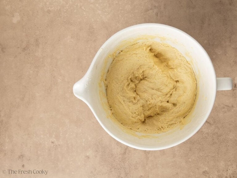 punched down cinnamon roll dough in white bowl.