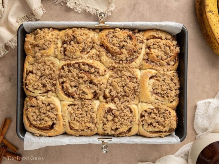 Golden baked cinnamon rolls in parchment lined pan.
