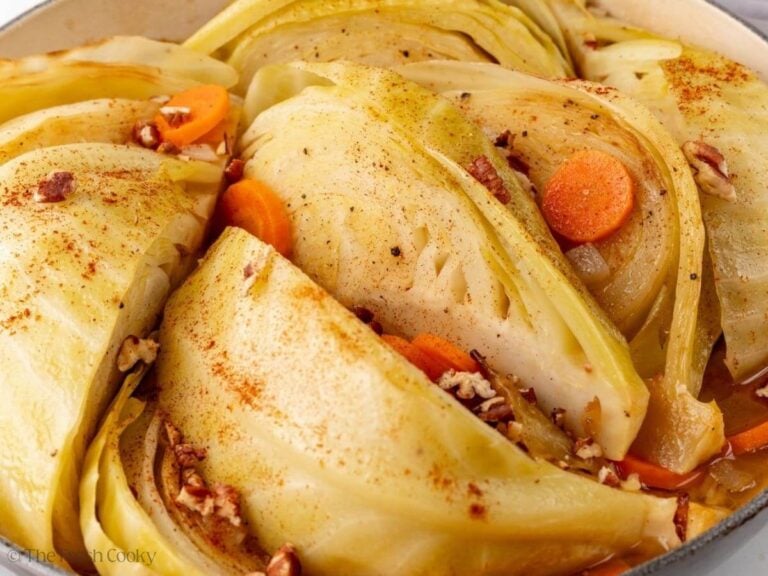Close up of braised cabbage wedges in a Dutch oven pot.