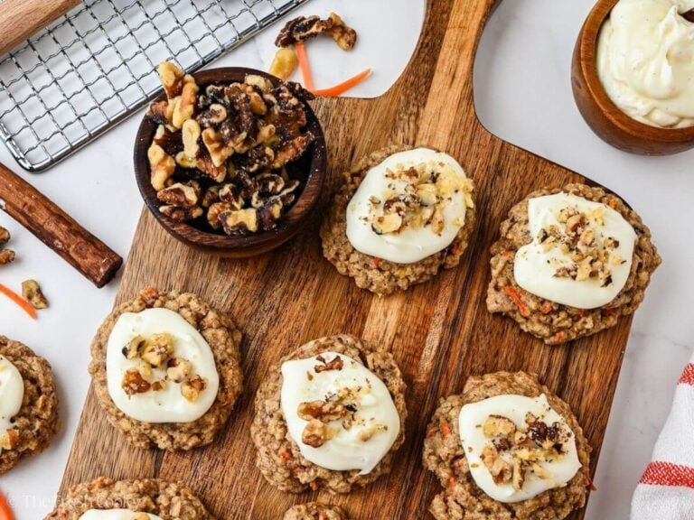 Carrot cake oat cookies on a wooden cutting board with extra walnuts.