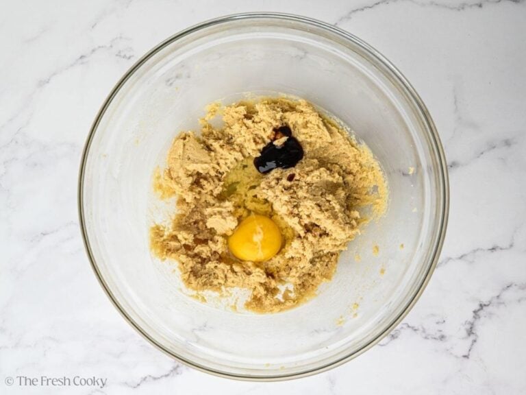 Hand mixer beating egg, butter, sugar, vanilla, and eggs.