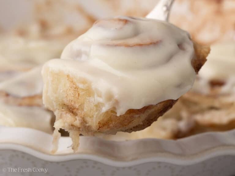 Crescent roll cinnamon roll on a spatula hovering over the rest of the rolls.