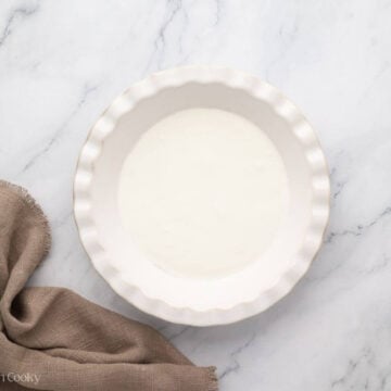 Overhead shot of a white pie dish with heavy cream in it.