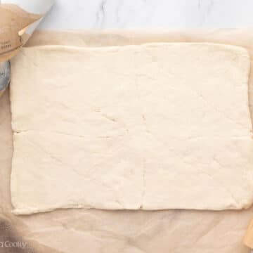 Crescent roll dough rolled out on a parchment paper.