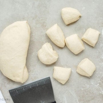 Dividing dough into even balls to pinch together to make yeast rolls.