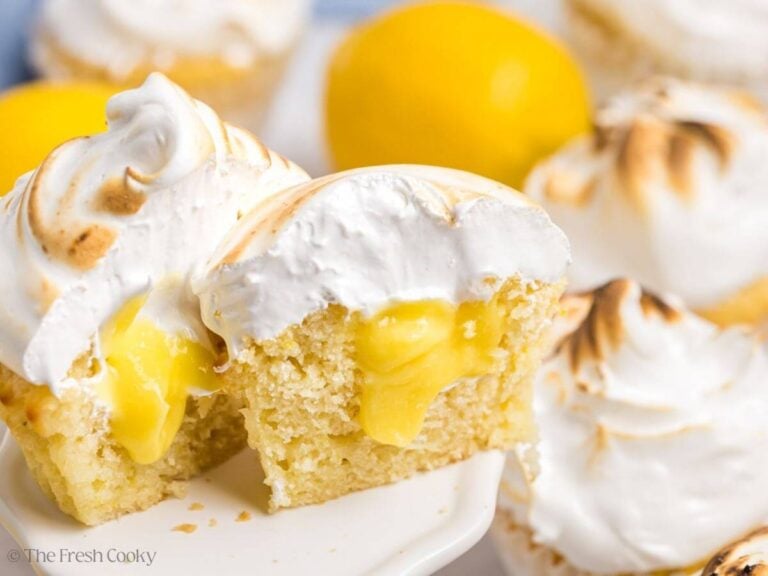 A lemon meringue cupcake cut open on a small pedestal.