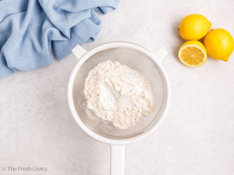 A sieve with dry ingredients in it for lemon meringue cupcakes.