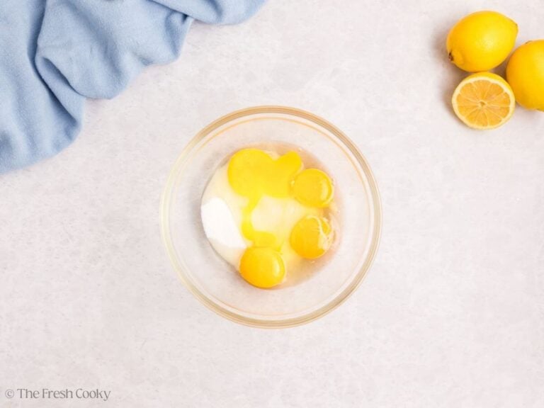 A glass bowl with eggs, egg yolks, sugar, and lemon juice.