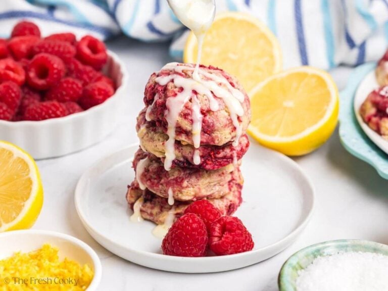 Stack of lemon raspberry cookies, with a spoon drizzling glaze over the top.