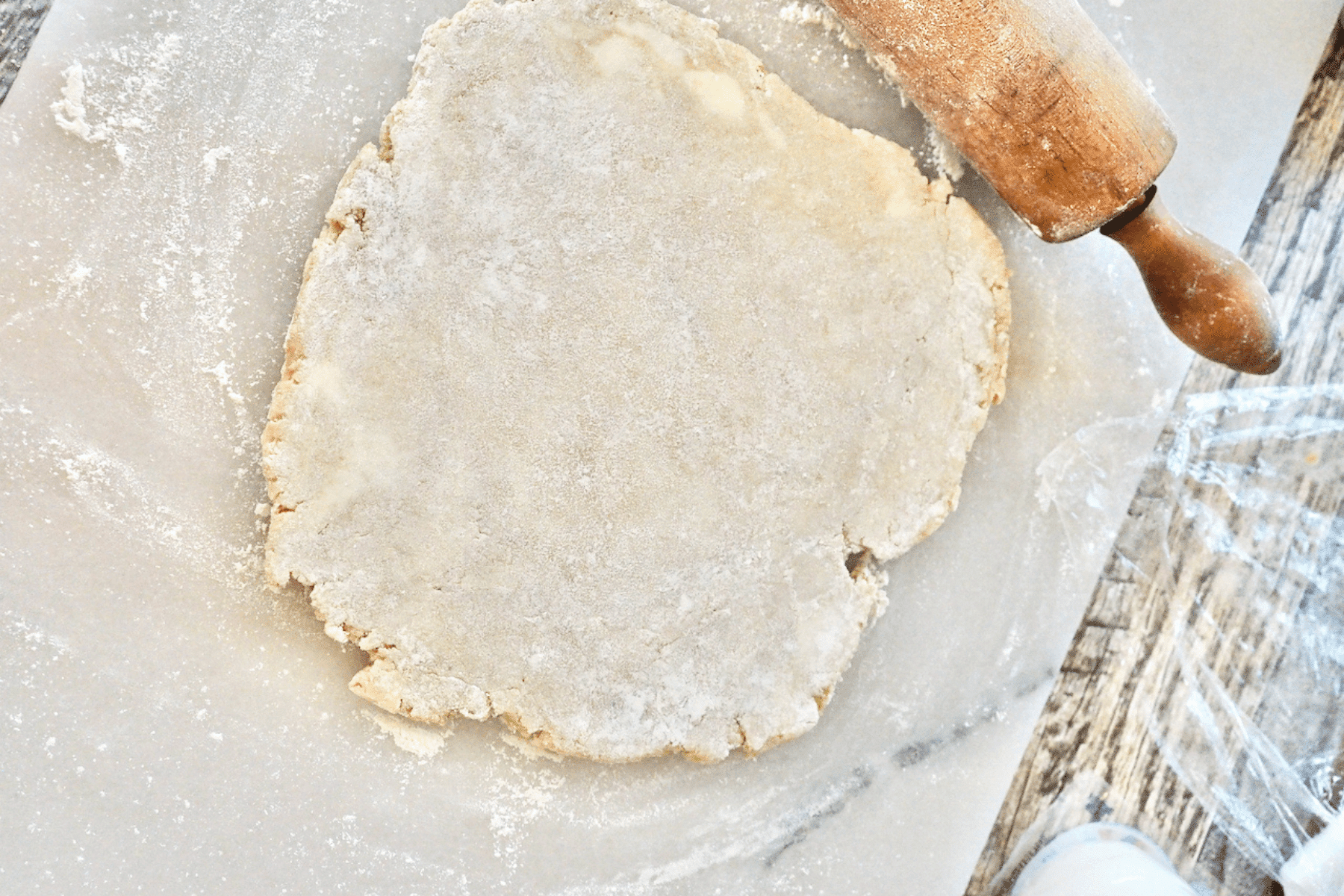 Rolling out pizza crust dough for springform pan on marble.