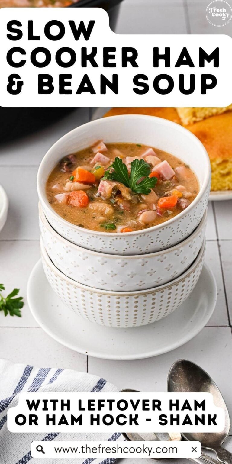 Stack of three pretty bowls with the top one filled with rich, creamy ham and bean soup with corn bread in background, to pin.
