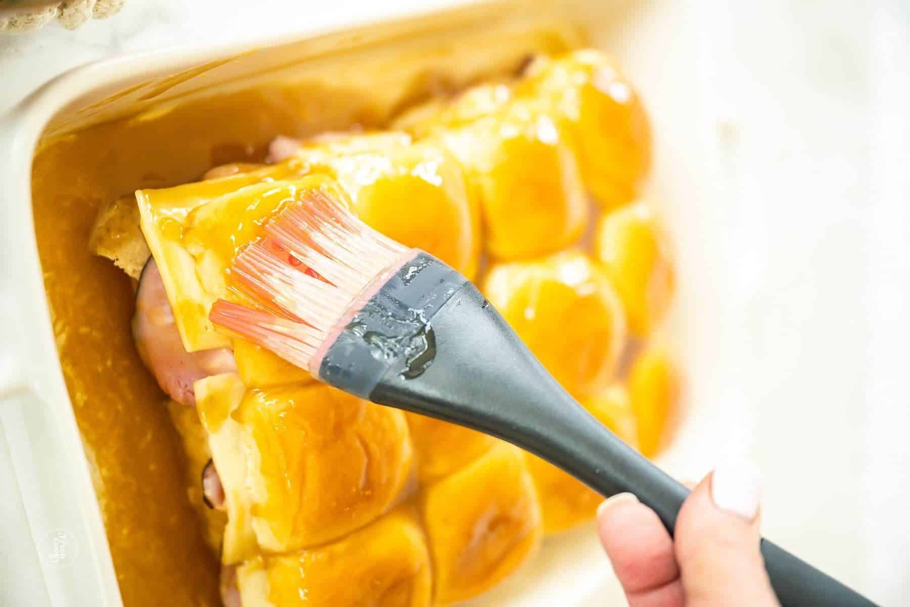 Brush sauce into the cracks and sides of the ham and cheese sliders.