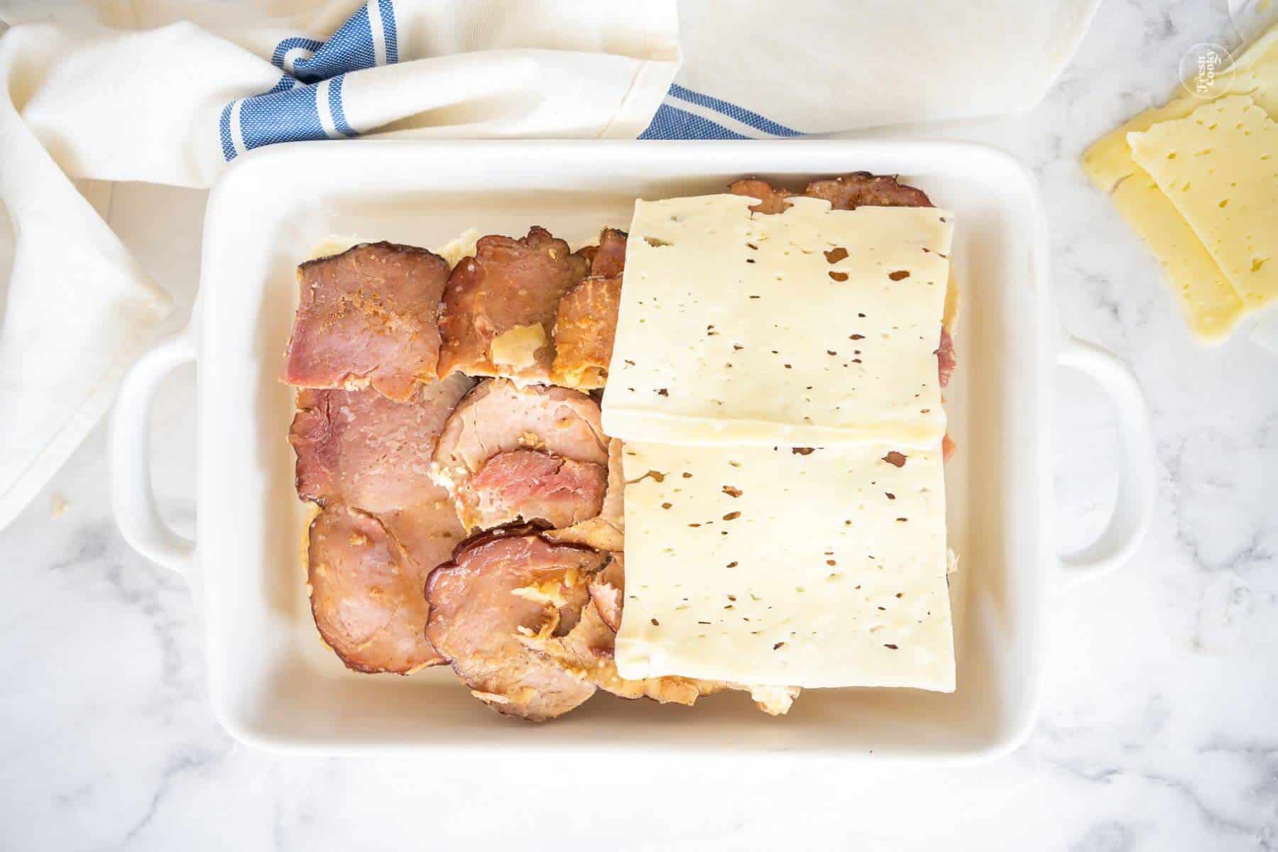 Leftover honeybaked ham on Hawaiian rolls with a few slices of Swiss cheese being layered on top.