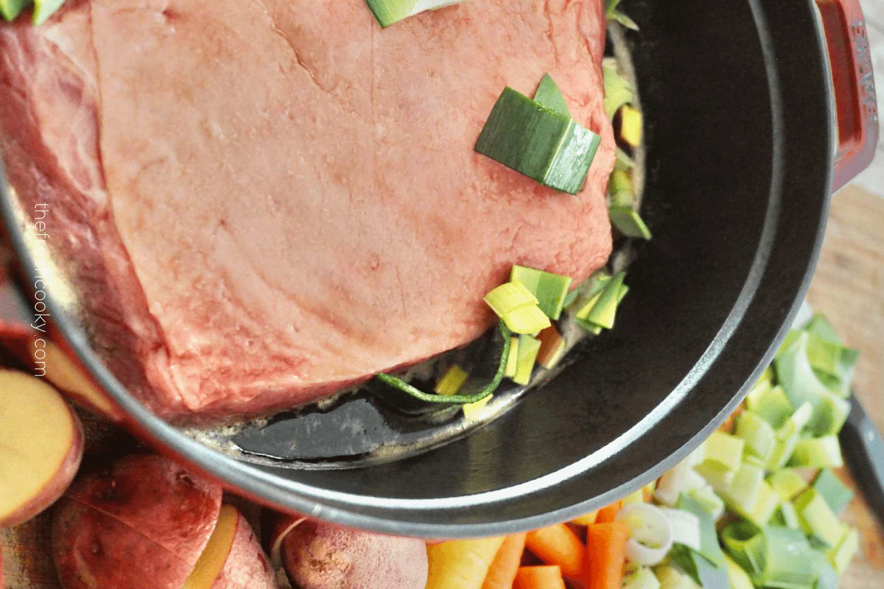 Adding leeks to the beer and corned beef in dutch oven for baked corned beef recipe.