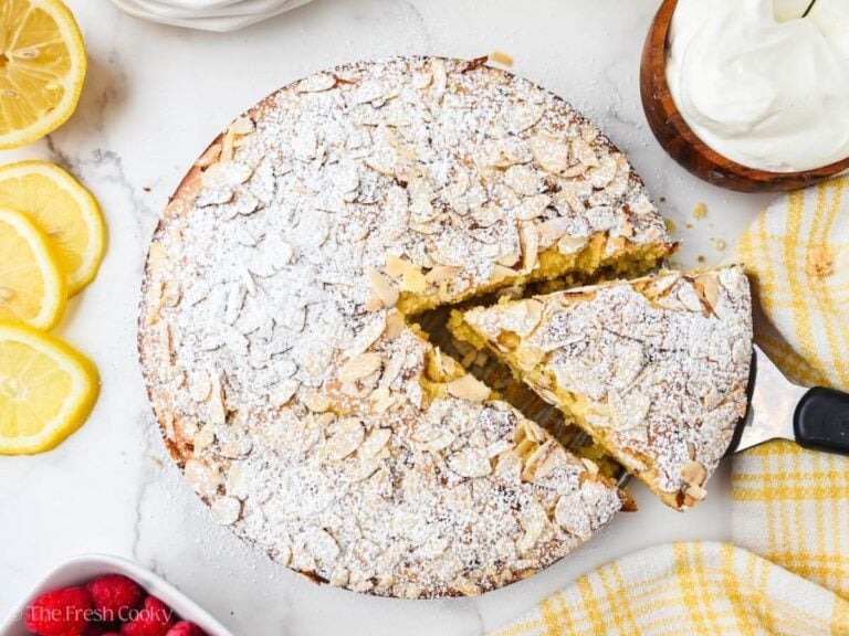 A slice of almond flour olive oil cake being removed with a metal spatula.
