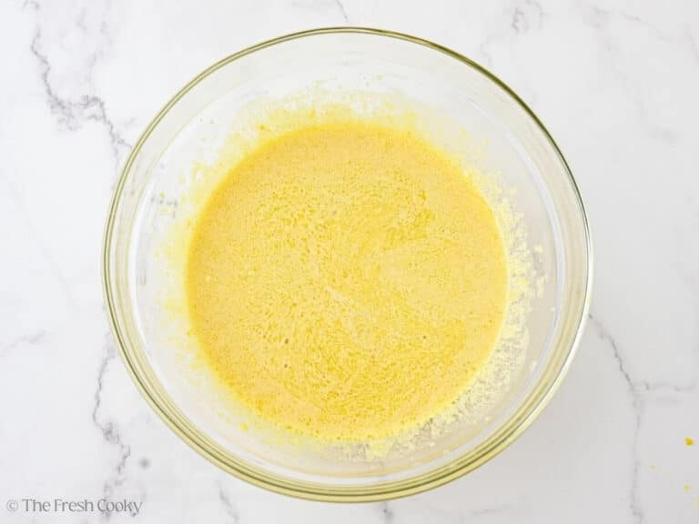 A glass bowl with wet ingredients for almond flour olive oil cake.