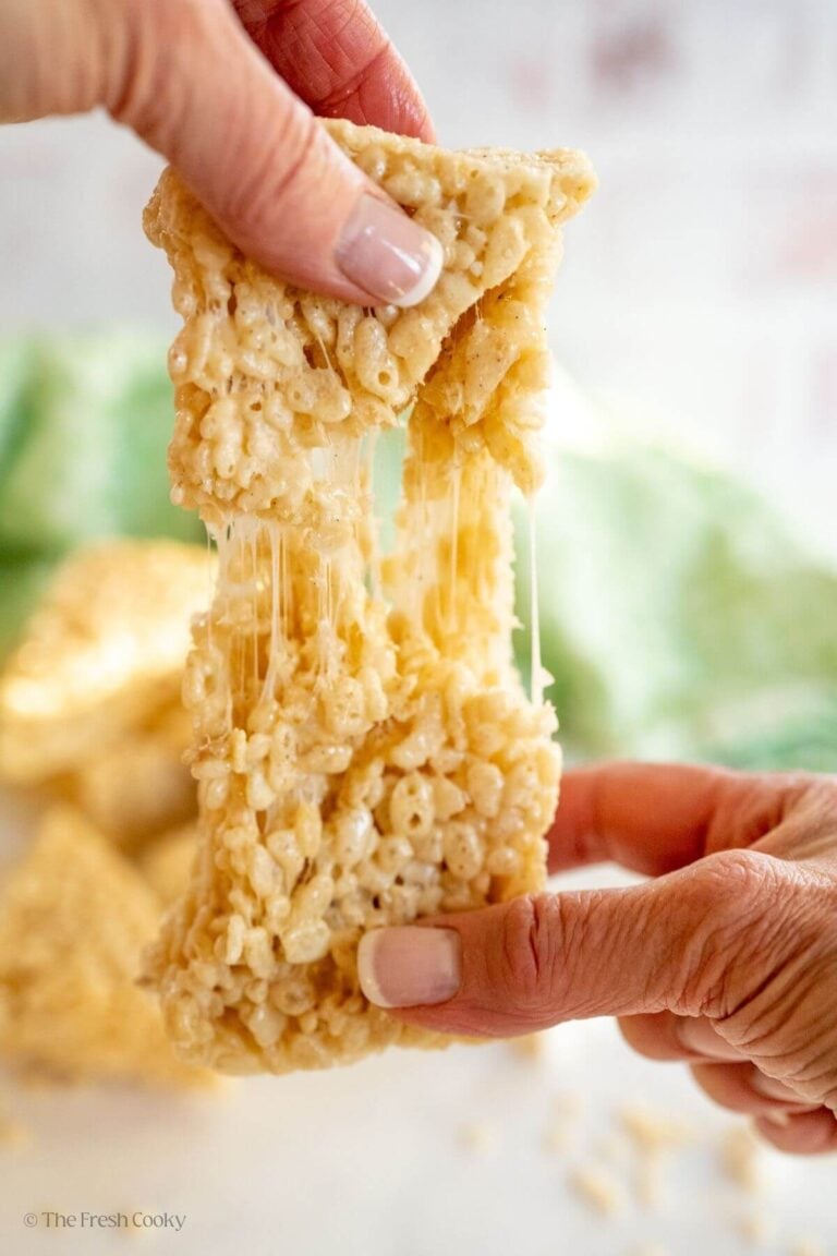 Hands pulling a rice krispie treat apart, showing ooey-gooey treats.