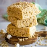 Stack of three thick, brown butter rice krispie treats on a little wooden board.