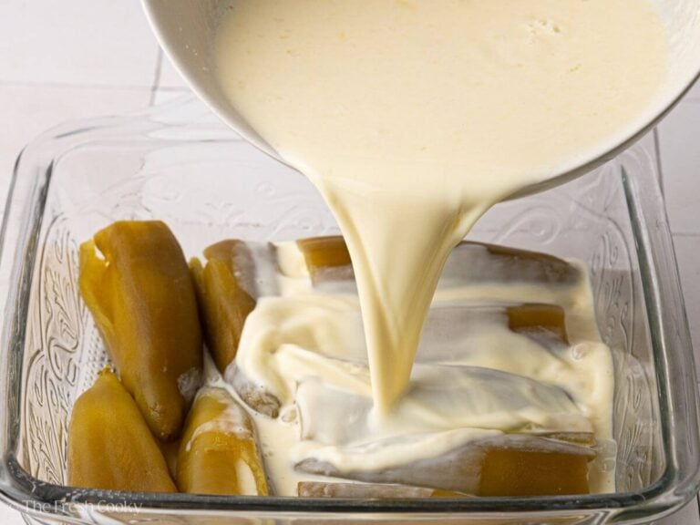 Pouring egg batter over chiles.