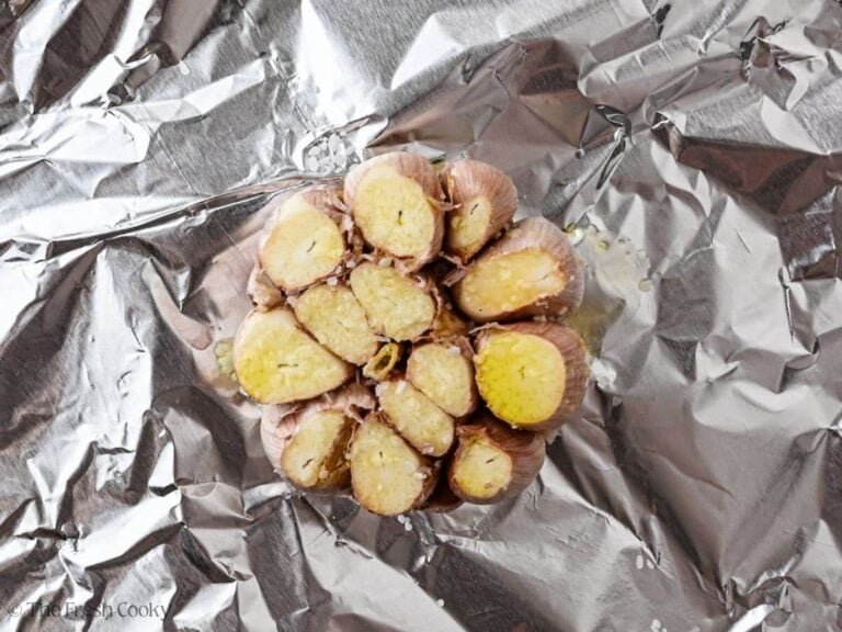 Whole bulb of garlic with top sliced off drizzled with olive oil and salt on foil.