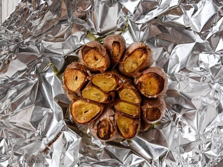 Golden roasted garlic on aluminum foil.