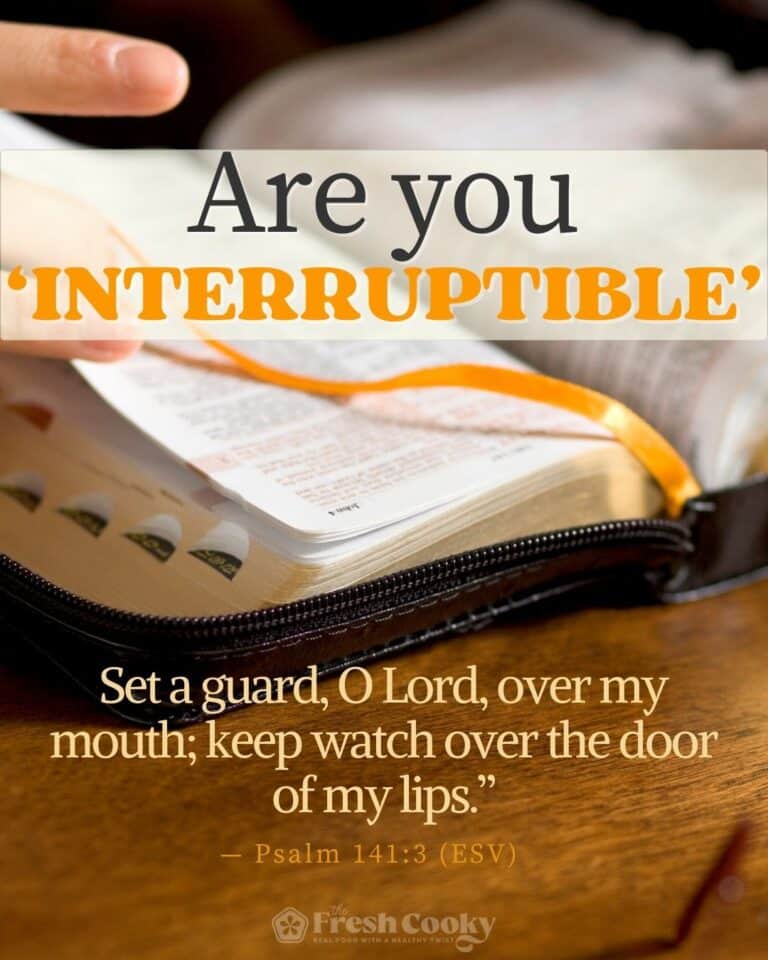 A Bible on a wooden table, open with a hand grabbing an orange bookmark, and words saying, "Are you interruptible" on it, for pinning.