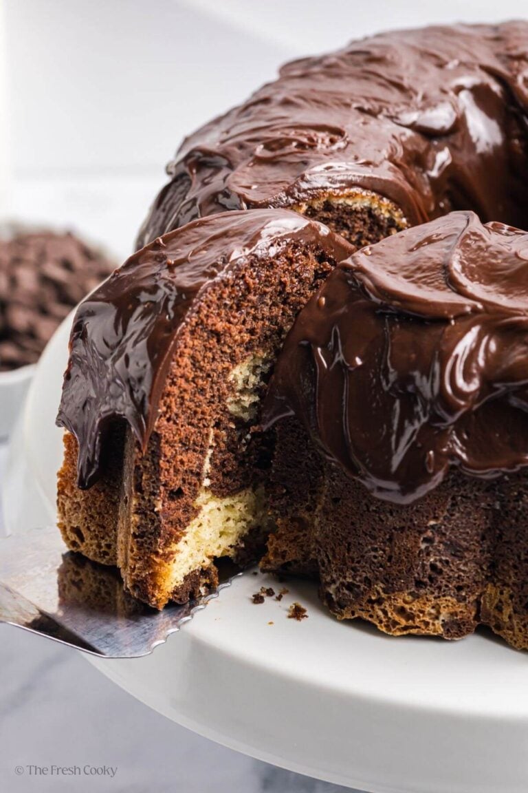 A slice out of the marble bundt cake with chocolate ganache on top.