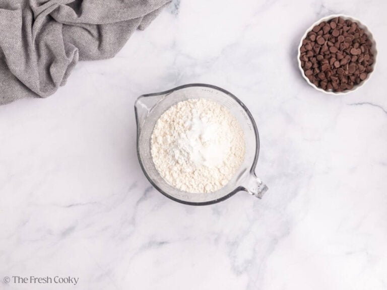 A glass measuring cup with dry ingredients for marble bundt cake.