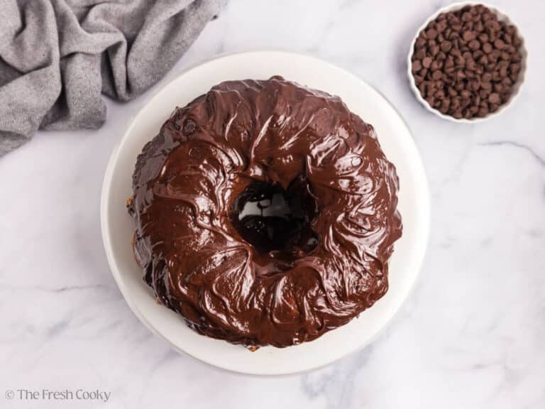 Overhead image of marble bundt cake on a white cake stand with a white bowl of chocolate chips.