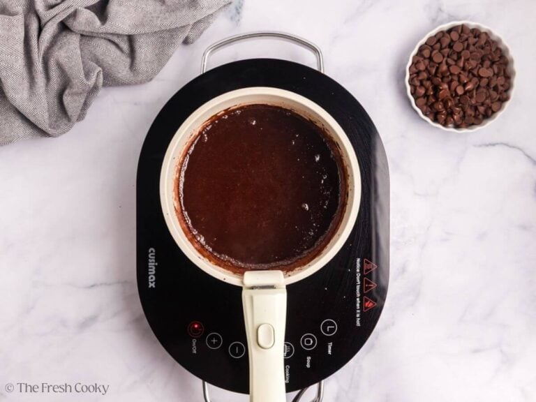 An induction burner with melted chocolate in a white saucepan.