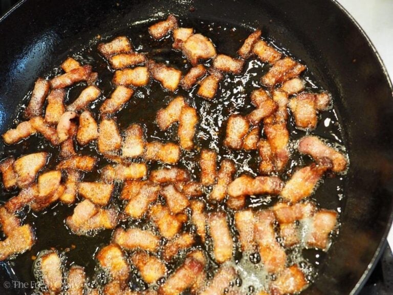 Bacon pieces crisping in pan.