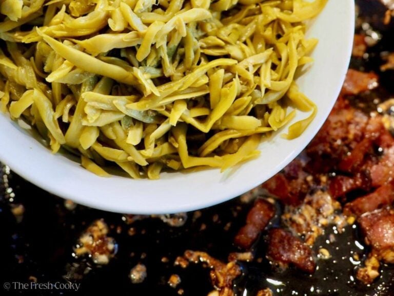 Adding drained green beans to the pan of bacon.