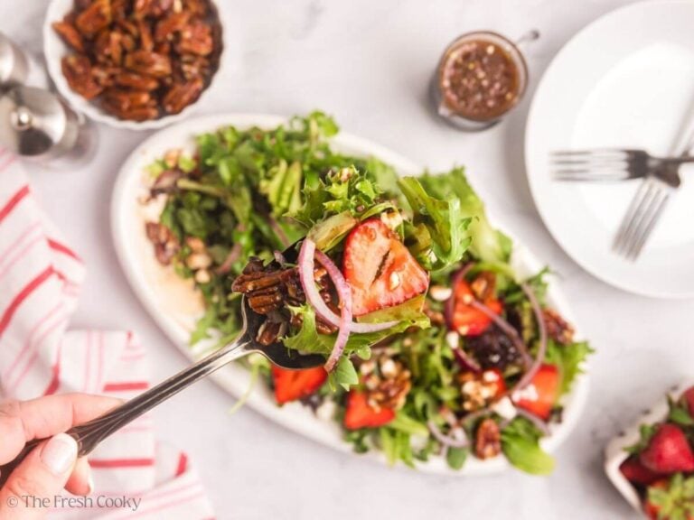 Salad tongs and tossed strawberry goat cheese salad.