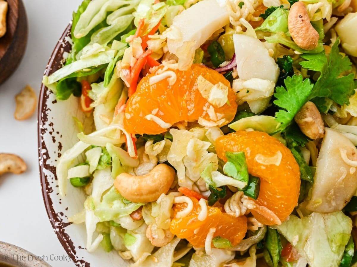 Close up of Ramen noodle salad showing chicken, cashews, cabbage, mandarin orange segments.