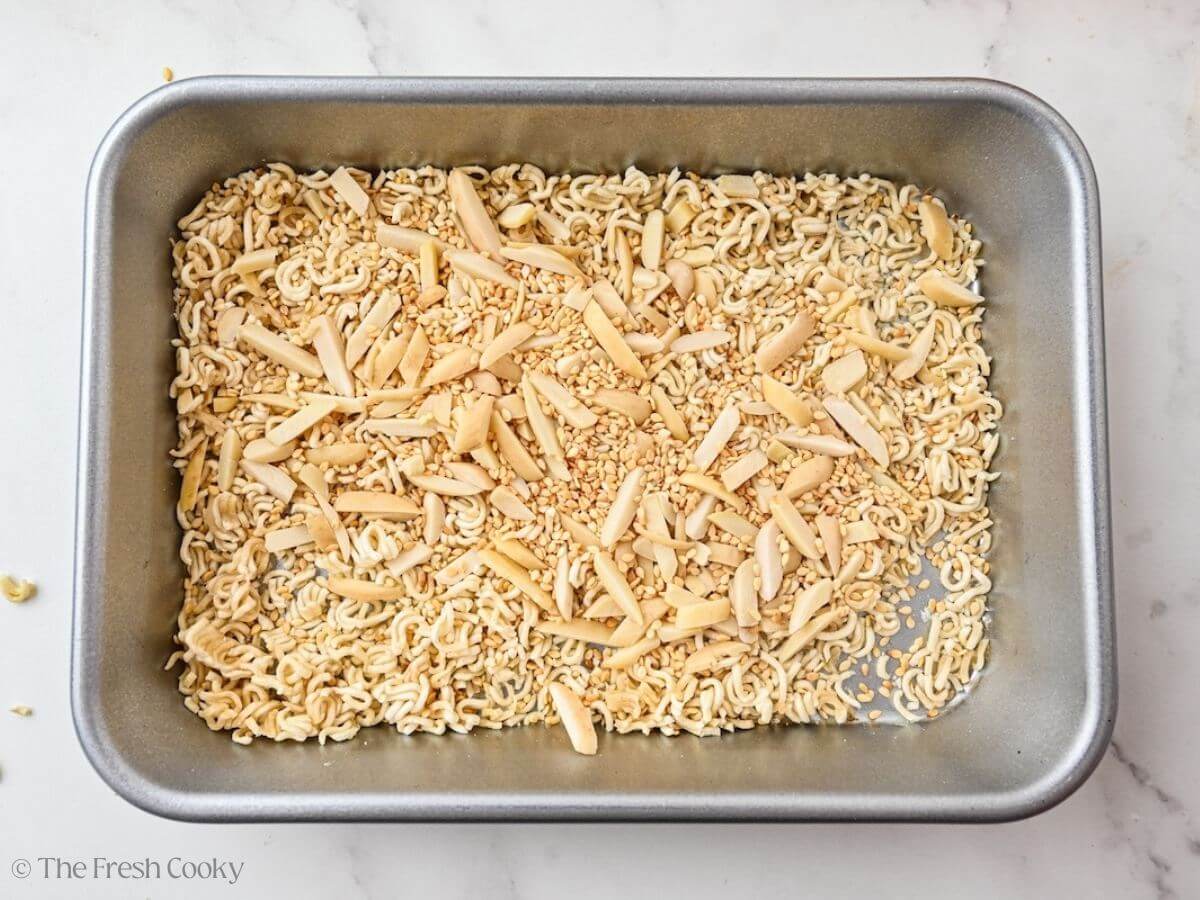 Ramen noodles, slivered almonds and sesame seeds in pan for toasting.