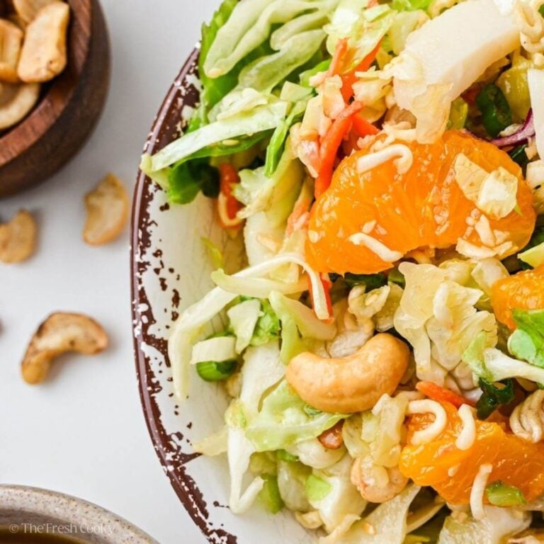 Close up of ramen noodle salad with cabbage, mandarin oranges, cashews, cilantros, tossed in a sweet Asian dressing.